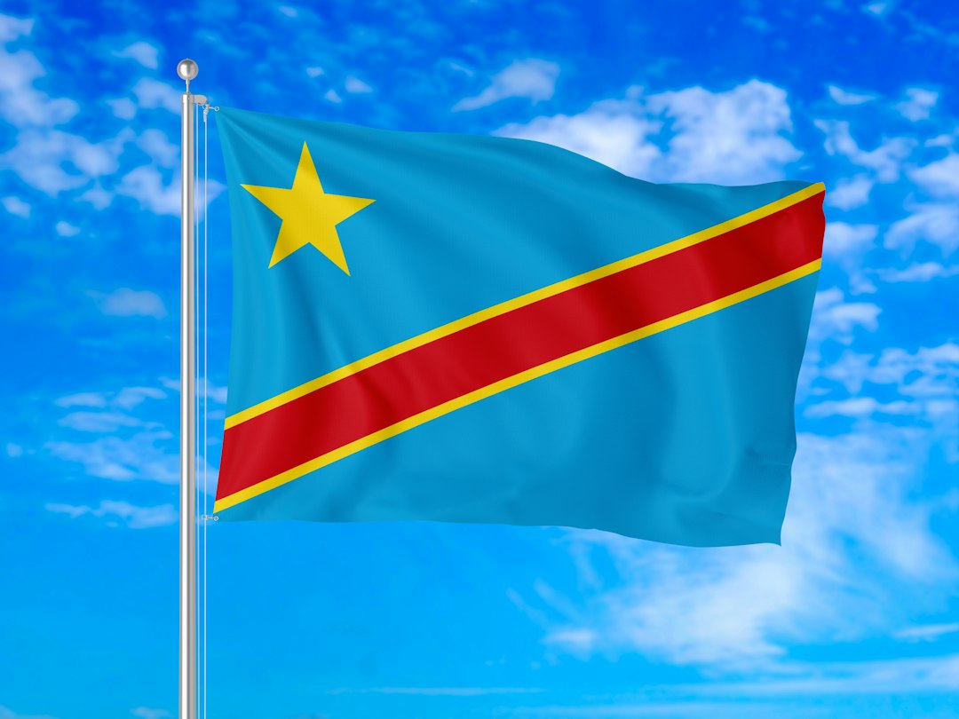 The blue, red and yellow flag of the Democratic Republic of Congo flying against a bright blue sky, representing the country’s Ebola emergency.