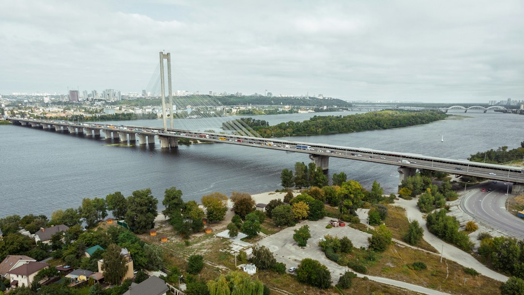 Kyiv’s South Bridge stretching across the Dnipro River in bright daylight, illustrating Russia’s campaign against the capital’s river crossings